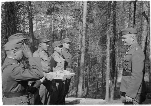Kenraali Raappana sai 50-vuotislahjaksi Otto Kemppaisen 
puusta tekemän kahvikaluston. Tekijä itse luovuttajien joukossa 
äärimmäisenä oikealla. Vastaava kalusto luovutettiin myös marsalkka 
Mannerheimille. (SA-Kuva)